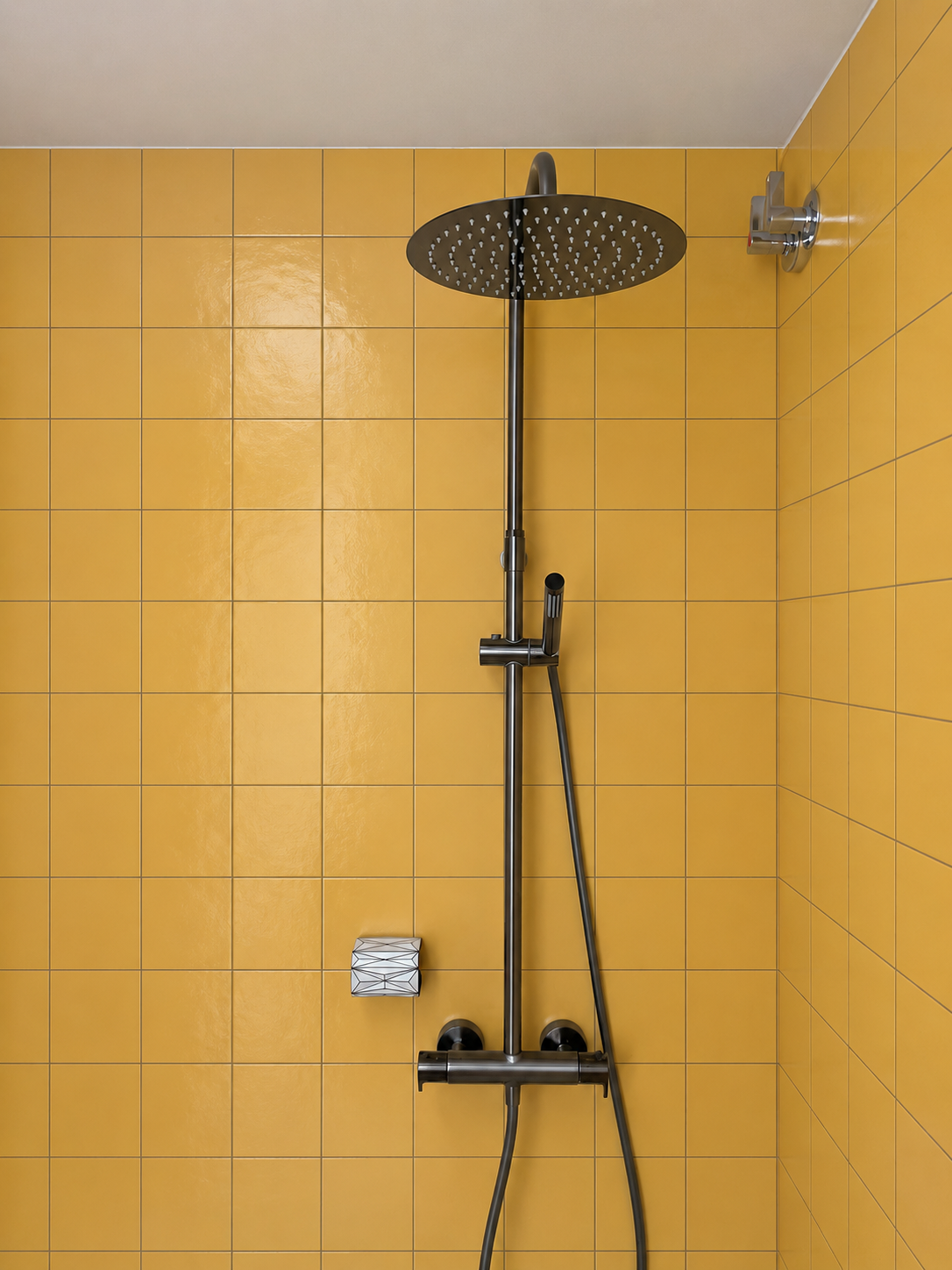 Jabonera O instalada abajo a la izquierda de la barra en una ducha amarilla con el rociador superior visible
