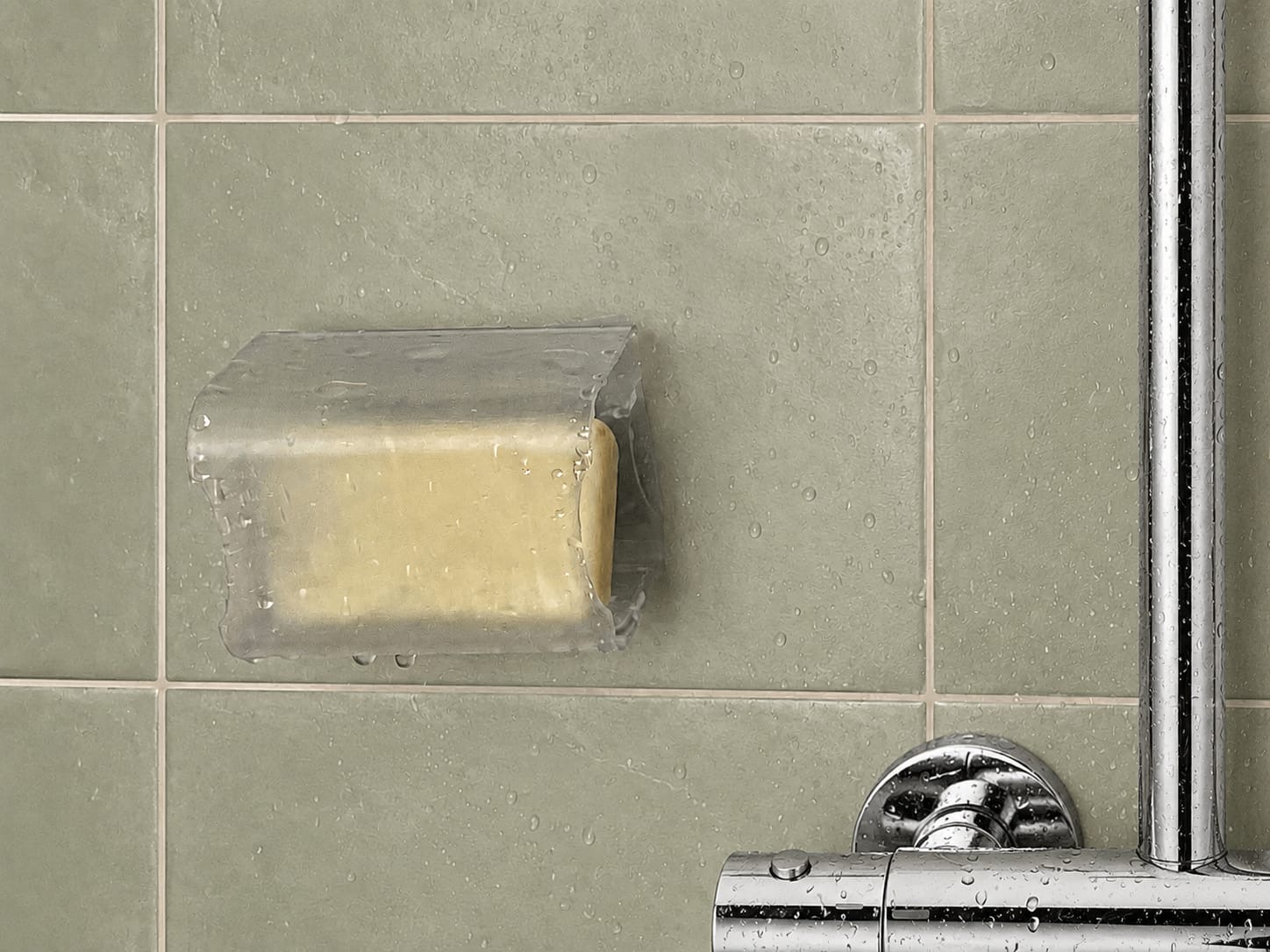 Jabonera O instalada en la pared de una ducha con azulejos verdes, protegiendo la pastilla del agua directa